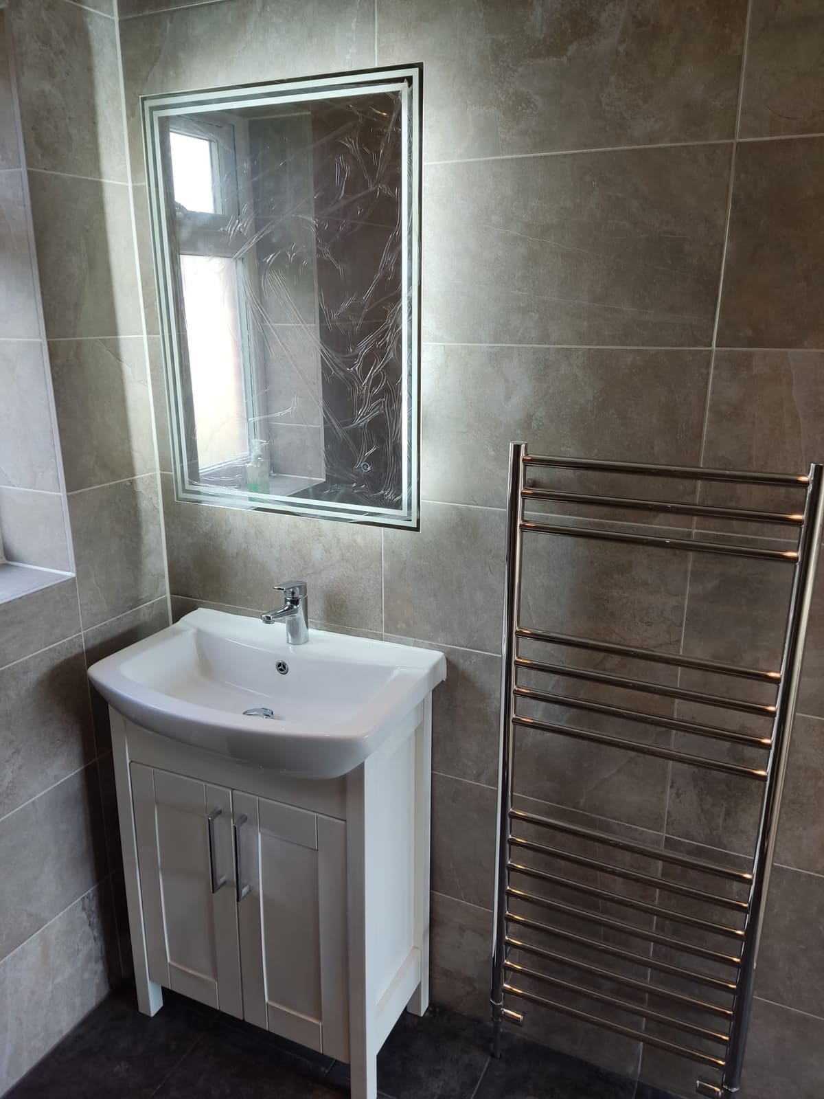 Bathroom vanity unit with LED mirror and chrome heated towel rail installation