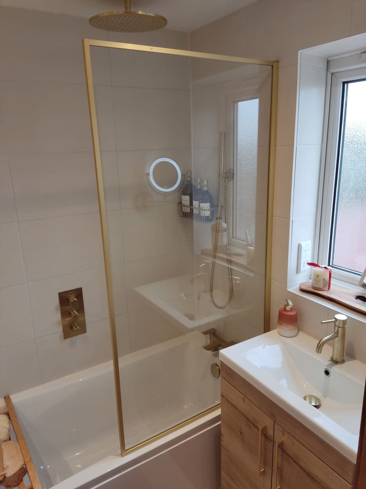 Modern bathroom with brushed brass shower over bath and oak vanity