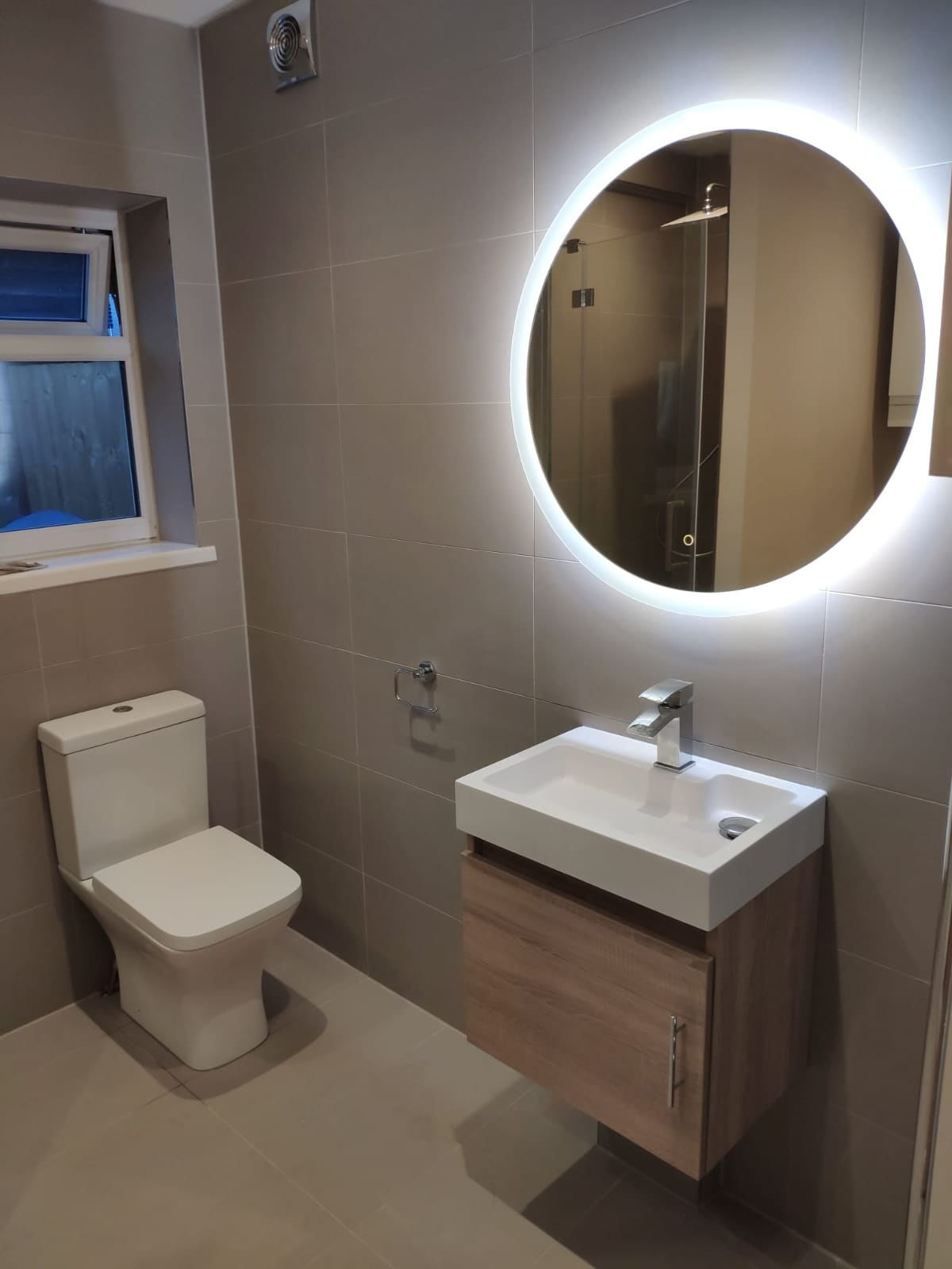 Modern cloakroom WC with round LED mirror and wall-hung basin unit