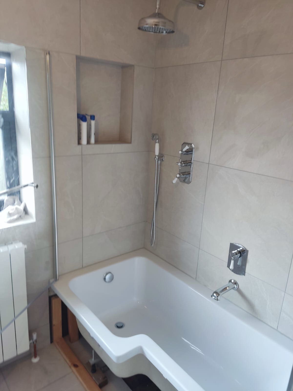 Traditional stone-effect tiled bathroom with chrome rainfall shower over bath